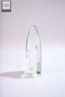 un vase en verre transparent à la base incurvée, posé sur une surface blanche