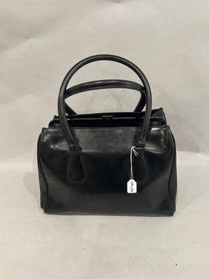 a black handbag with a tag on it sitting on a white surface
