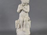 marble statue of a boy sitting on a rock with his hands clasped