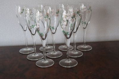 six wine glasses with flowers are lined up on a wooden table