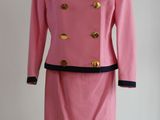 robe rose et noire avec des boutons dorés, posée sur un socle de mannequin