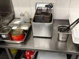 stainless steel work table with two deep fryers and a sink