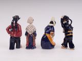 three figurines of people dressed in different outfits and hats