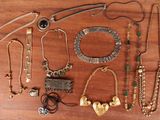 many different necklaces and bracelets laid out on a table