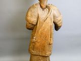 une vieille statue en bois représentant un homme avec un sac sur l'épaule