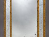 a gold framed mirror on a grey background