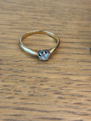a gold ring with a diamond on top of a wooden table