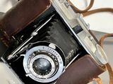a brown leather bag with a camera on top of it
