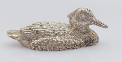 a silver duck figurine sitting on top of a white surface