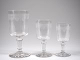three empty wine glasses sitting next to each other on a white surface