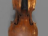 an old violin with a black bow hanging on a wall