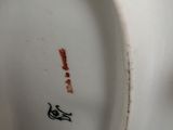 a close up of a white vase with a bird on it