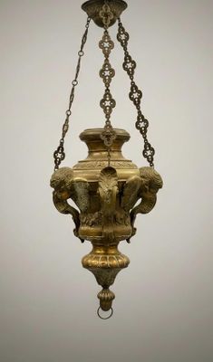 un lustre ancien en laiton suspendu à une chaîne sur un fond gris