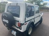 a white jeep parked in a parking lot with a tire cover on it ' s back