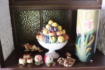 a white vase filled with fruit on top of a wooden shelf