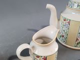 a tea pot and a plate with a cup and saucer on it