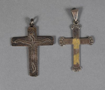 deux pendentifs en forme de croix, en argent et en or, sur un fond gris