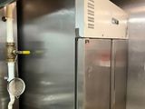 stainless steel refrigerators in a commercial kitchen with pipes and valves
