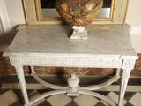 a marble table with a vase on it in front of a mirror