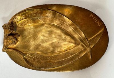 une plaque dorée ornée d'une feuille sur un fond blanc
