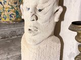 une statue représentant la tête d'un homme, posée sur une étagère à côté d'un vase