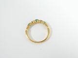 a close up of a gold ring with emerald stones
