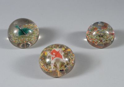 three glass marbles sitting on top of each other on a white surface
