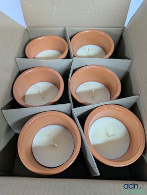 candles in clay pots in a cardboard box on a table