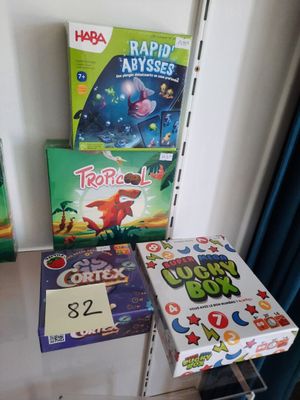 several children ' s board games are sitting on a shelf in the corner of a room