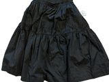 La jupe est noire et comporte une étiquette blanche.