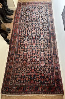un tapis posé à même le sol dans un couloir, avec une paire de bottes posée par terre