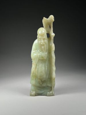 a green jade figurine of a man holding a staff
