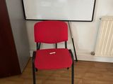 a red chair sitting in front of a white board