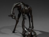 bronze statue of a giraffe and a dog on a grey surface