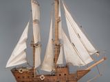 a wooden model of a sailboat with white sails