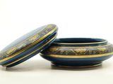 a blue and gold bowl with a lid on a white surface