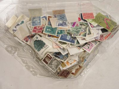 de nombreux timbres différents dans une boîte en plastique posée sur la table