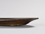bronze plate with a bird on top of it on a white surface