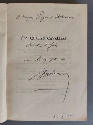 un livre ouvert, dont une page est recouverte d'une écriture manuscrite, posé sur une table