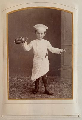 an old photo of a little boy in a chef ' s uniform