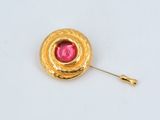 a close up of a gold pin with a pink stone in the center