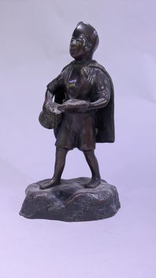 une statue représentant un homme tenant un panier, assis sur un rocher