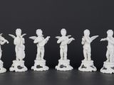 six white figurines of people standing in a line on a black surface