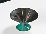 a small metal object with a green base on a white table