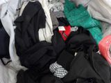 a pile of clothes that is sitting on a bed