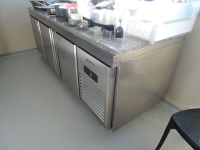a stainless steel counter top with a sink and a refrigerator
