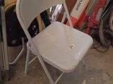 a white folding chair sitting in a room next to a pile of junk