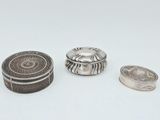 trois bijoux en argent posés sur une surface blanche, sur fond blanc