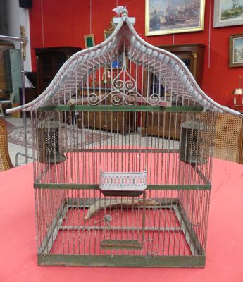 un oiseau dans une cage posée sur une table recouverte d'une nappe rouge