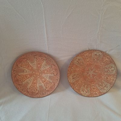 Il s'agit de deux assiettes ornées de motifs, posées sur une surface blanche.
